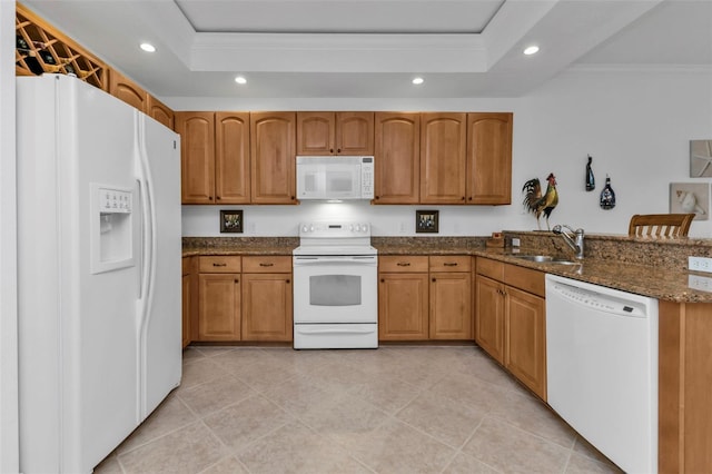 kitchen with ornamental molding, white appliances, a tray ceiling, sink, and dark stone countertops