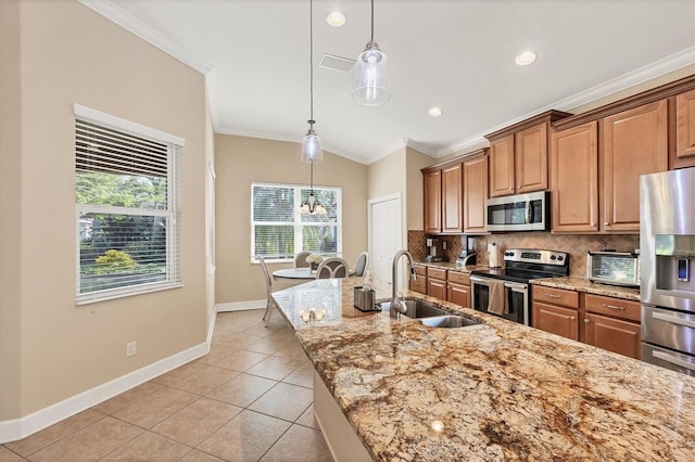 kitchen featuring light stone countertops, pendant lighting, stainless steel appliances, and sink