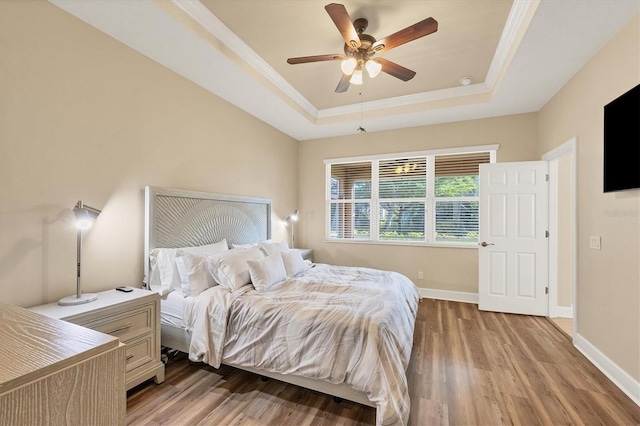 bedroom with light hardwood / wood-style floors, a raised ceiling, ceiling fan, and ornamental molding