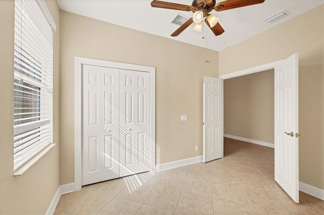 unfurnished bedroom with ceiling fan, light tile patterned floors, and a closet