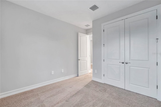 unfurnished bedroom featuring light colored carpet and a closet