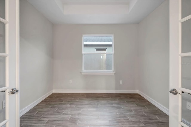 unfurnished room featuring a raised ceiling and dark hardwood / wood-style flooring