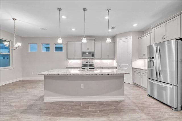 kitchen with pendant lighting, stainless steel appliances, and a kitchen island with sink