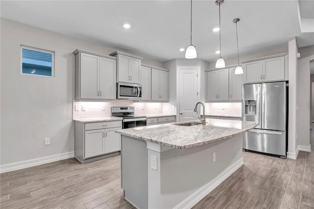 kitchen featuring light stone counters, sink, stainless steel appliances, and light hardwood / wood-style flooring