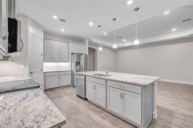 kitchen featuring pendant lighting, sink, light hardwood / wood-style flooring, an island with sink, and stainless steel appliances