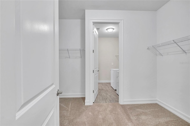 spacious closet with light carpet and separate washer and dryer