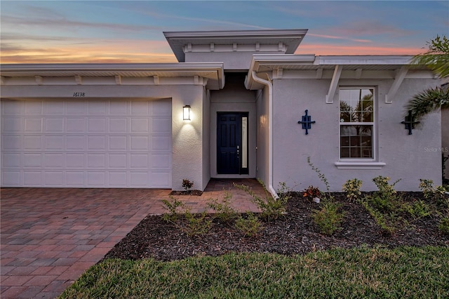 exterior entry at dusk featuring a garage