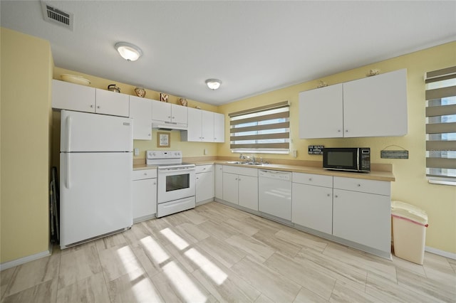 kitchen featuring sink, white cabinets, and white appliances