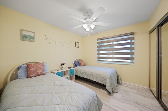 bedroom with a closet, light hardwood / wood-style flooring, and ceiling fan