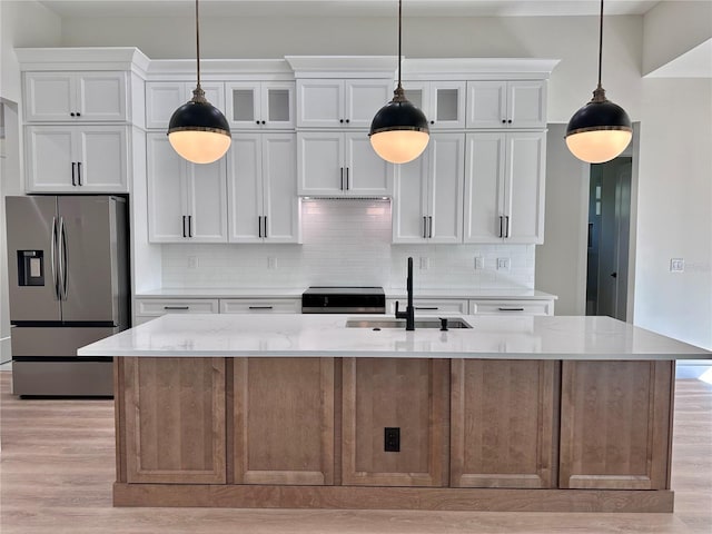 kitchen featuring white cabinets, light stone countertops, stainless steel appliances, and a kitchen island with sink