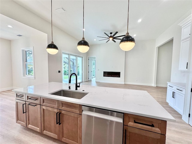 kitchen featuring dishwasher, sink, light stone counters, light hardwood / wood-style floors, and white cabinets