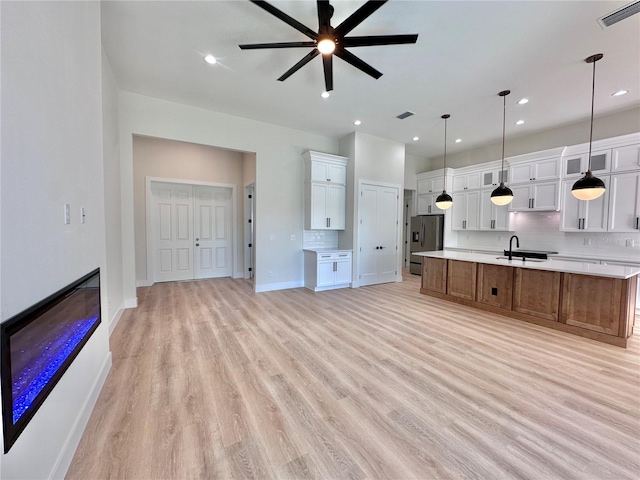 kitchen with white cabinetry, a large island, stainless steel refrigerator with ice dispenser, pendant lighting, and light hardwood / wood-style floors