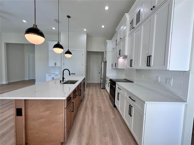 kitchen with light stone countertops, light wood-type flooring, pendant lighting, a large island with sink, and white cabinetry