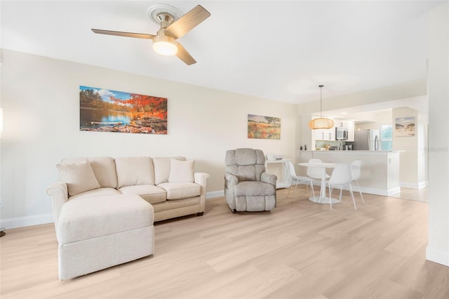 living room featuring ceiling fan and light hardwood / wood-style floors