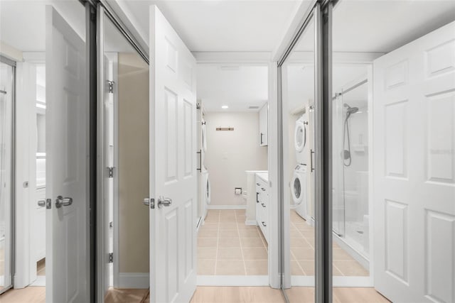 bathroom featuring tile patterned flooring, vanity, a shower with shower door, and stacked washer and clothes dryer