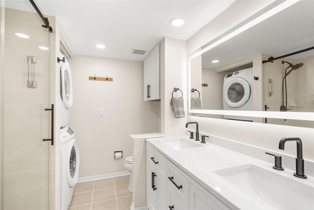 bathroom featuring vanity, a shower with door, tile patterned flooring, toilet, and stacked washer / drying machine