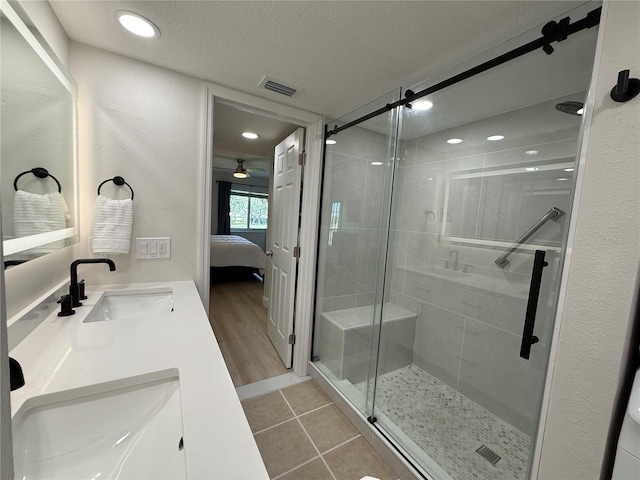 bathroom featuring ceiling fan, hardwood / wood-style floors, a textured ceiling, a shower with door, and vanity