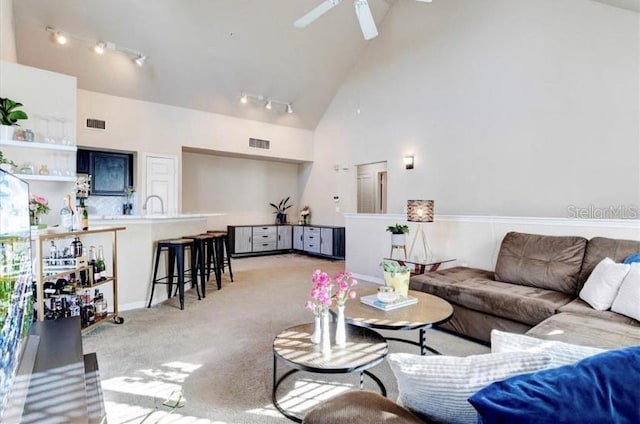 living room featuring ceiling fan, sink, rail lighting, high vaulted ceiling, and light colored carpet