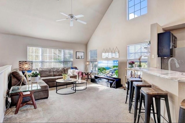 living room with light colored carpet, high vaulted ceiling, ceiling fan, and a healthy amount of sunlight