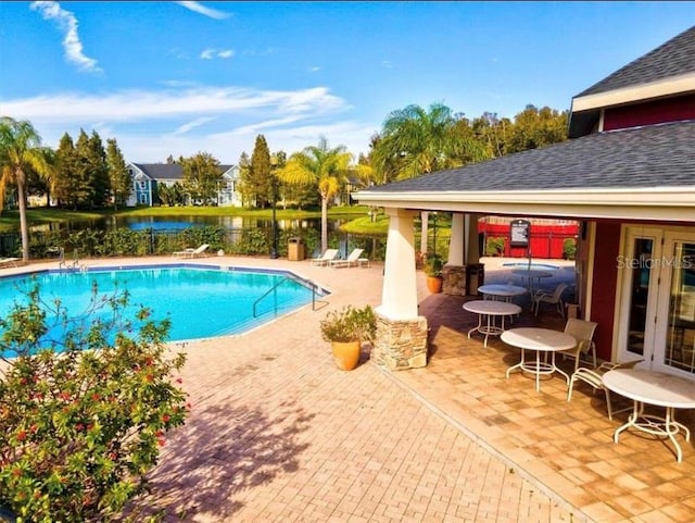 view of pool featuring a water view and a patio