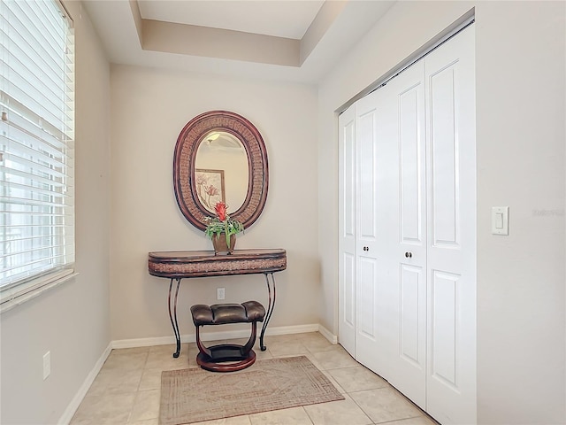 interior space with a raised ceiling and light tile patterned floors