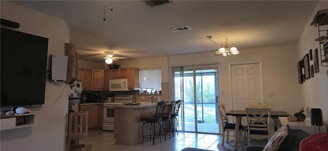 kitchen featuring light tile patterned flooring, a kitchen bar, kitchen peninsula, white appliances, and ceiling fan with notable chandelier