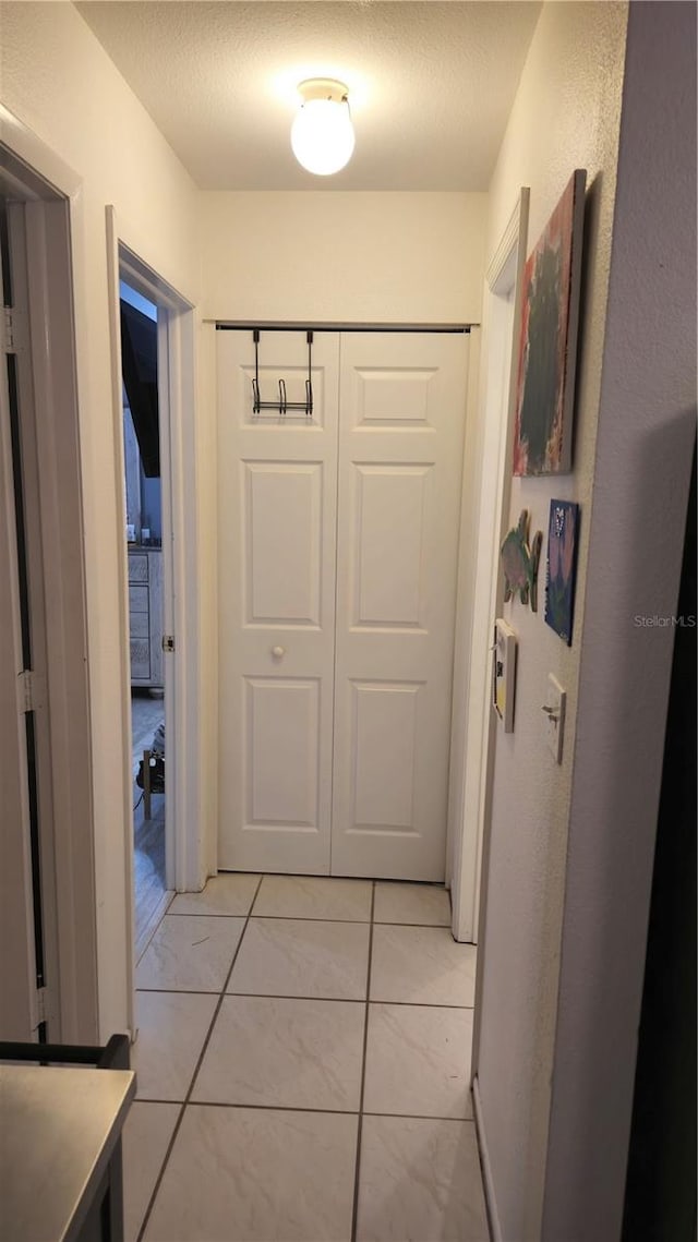 hall featuring light tile patterned flooring and a textured ceiling