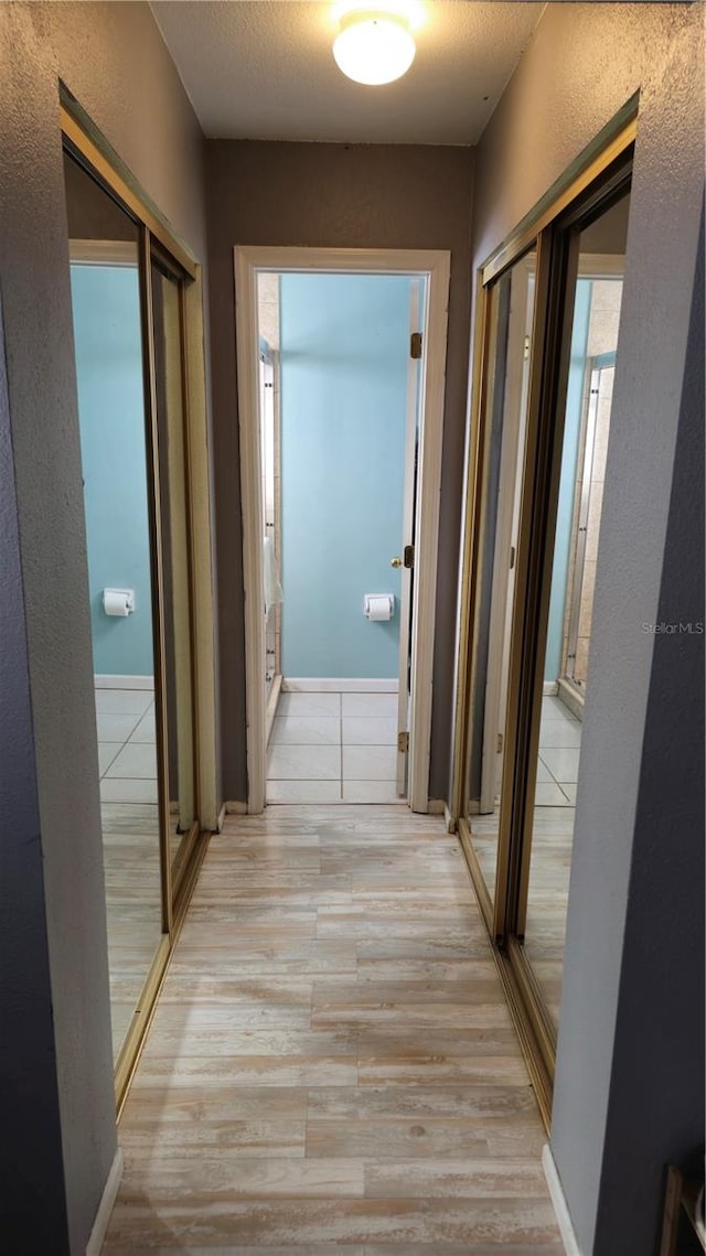 corridor with light hardwood / wood-style flooring and a textured ceiling