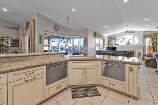 kitchen with vaulted ceiling, ceiling fan, sink, cream cabinets, and light tile patterned floors