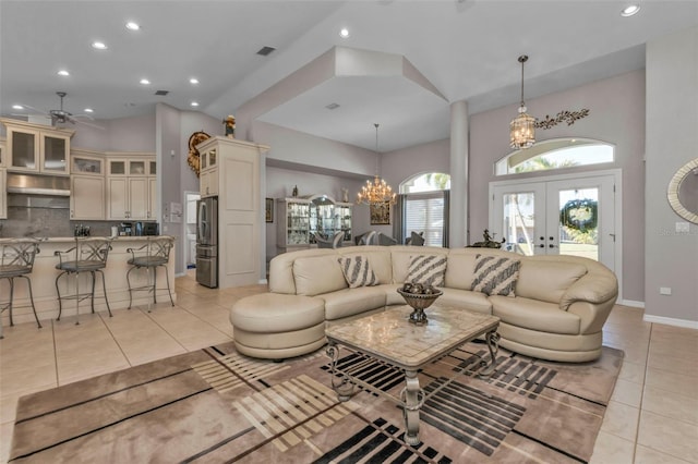 living room with ceiling fan with notable chandelier, light tile patterned floors, and french doors