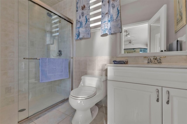 bathroom with tile patterned floors, an enclosed shower, vanity, tile walls, and toilet