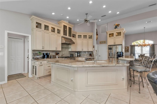 kitchen featuring a large island, sink, range hood, cream cabinets, and appliances with stainless steel finishes