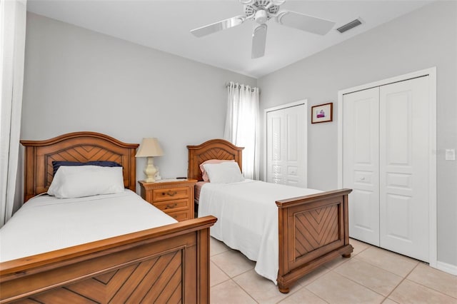 tiled bedroom featuring ceiling fan and multiple closets