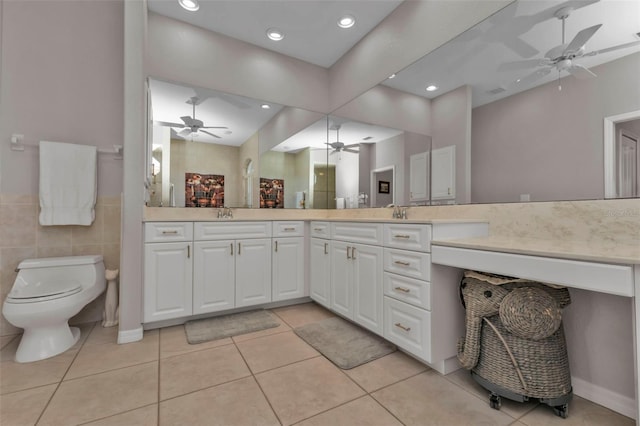 bathroom with tile patterned flooring, vanity, toilet, and tile walls