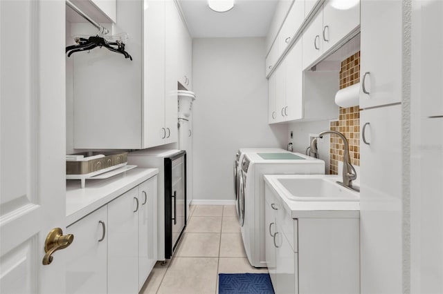 laundry room with washer and clothes dryer, light tile patterned flooring, cabinets, and sink