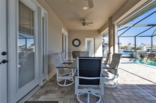 view of patio / terrace with a water view, ceiling fan, and a lanai