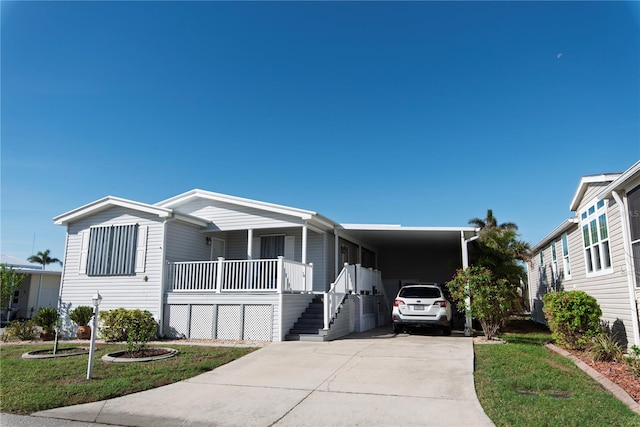 manufactured / mobile home with a carport, covered porch, and a front yard