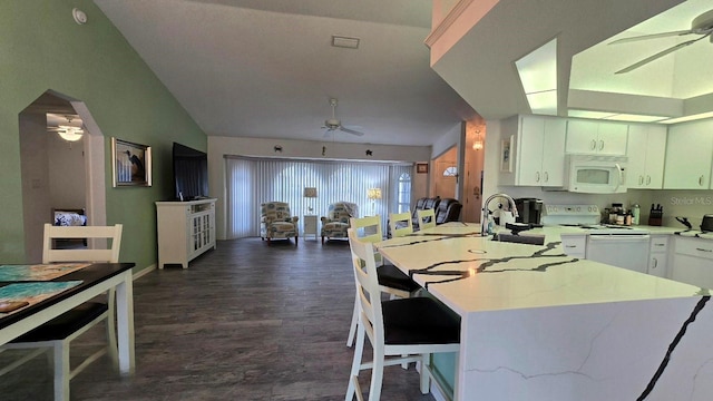 kitchen with lofted ceiling, white appliances, dark wood-type flooring, sink, and white cabinetry