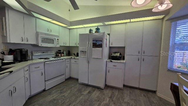 kitchen featuring white cabinets, lofted ceiling, white appliances, and dark wood-type flooring