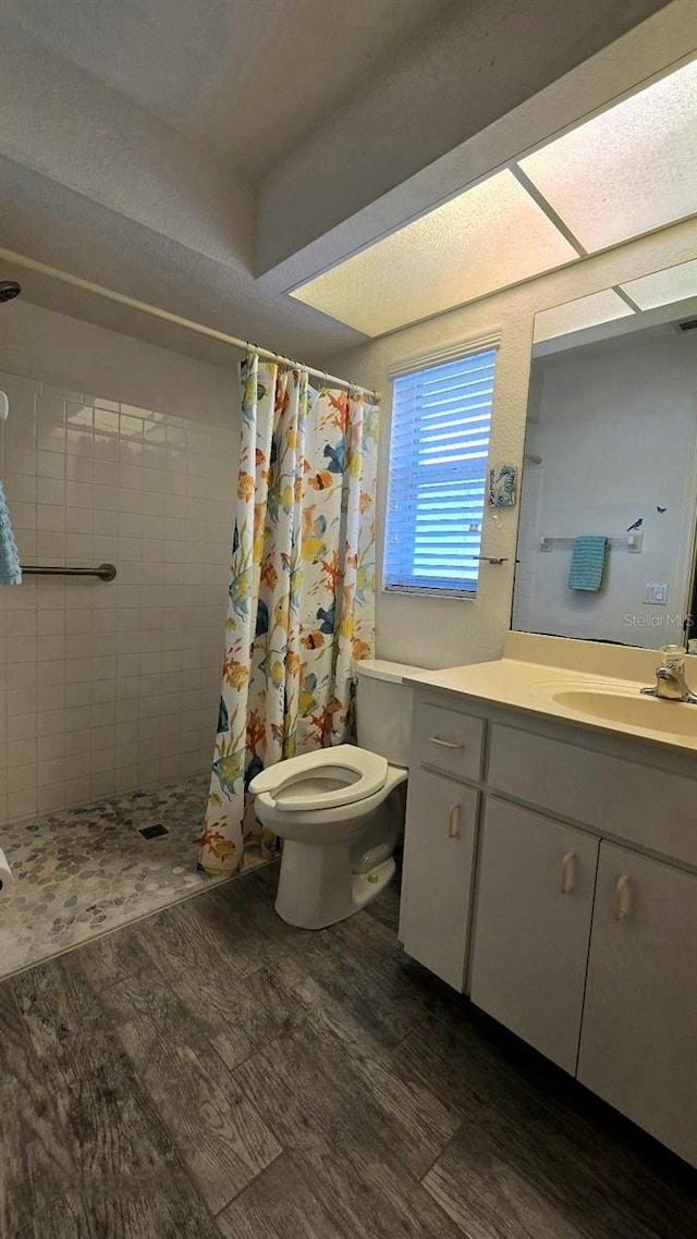 bathroom featuring hardwood / wood-style floors, vanity, toilet, a textured ceiling, and curtained shower