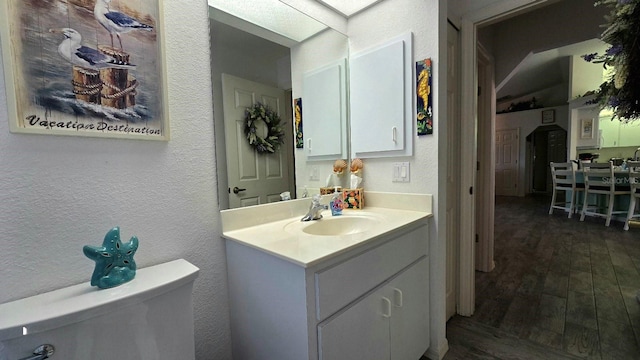 bathroom with hardwood / wood-style floors, vanity, and toilet