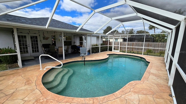 view of pool featuring glass enclosure, a patio, and french doors