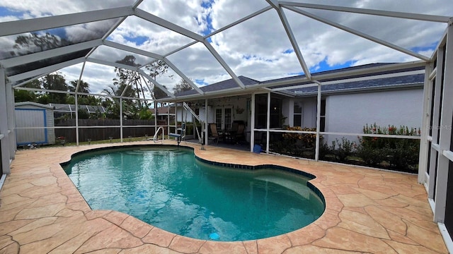 view of pool featuring a patio, glass enclosure, and a shed