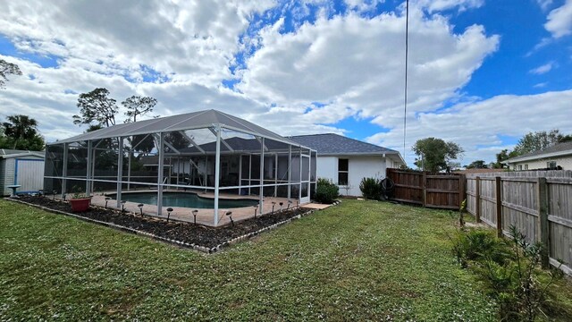 rear view of property featuring a yard, a fenced in pool, and glass enclosure