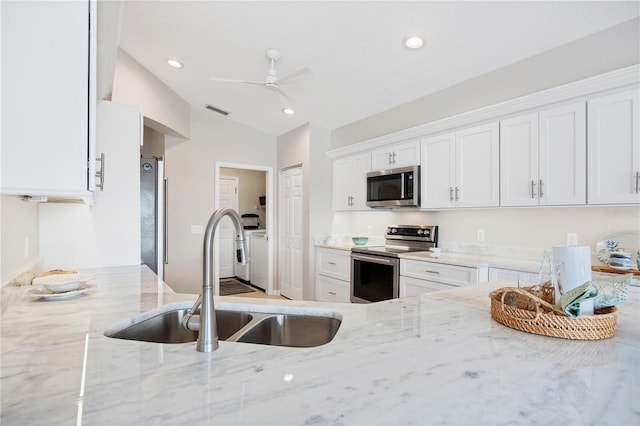 kitchen featuring sink, stainless steel appliances, light stone counters, lofted ceiling, and white cabinets