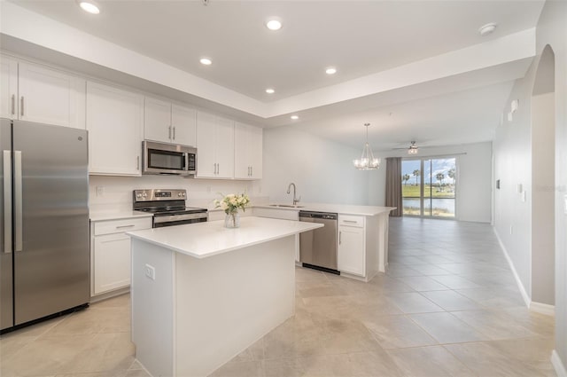 kitchen featuring kitchen peninsula, appliances with stainless steel finishes, ceiling fan with notable chandelier, sink, and pendant lighting