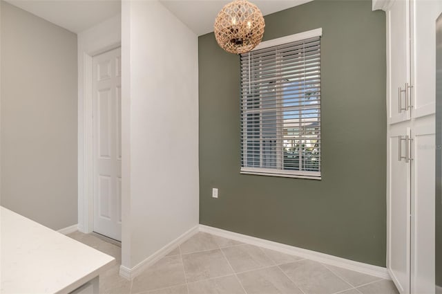 unfurnished dining area featuring light tile patterned floors and a chandelier