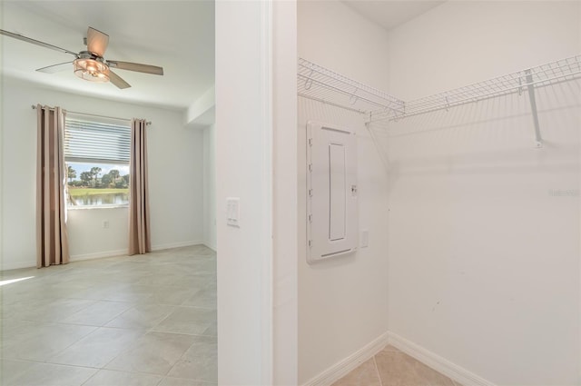 spacious closet featuring ceiling fan, light tile patterned floors, and electric panel