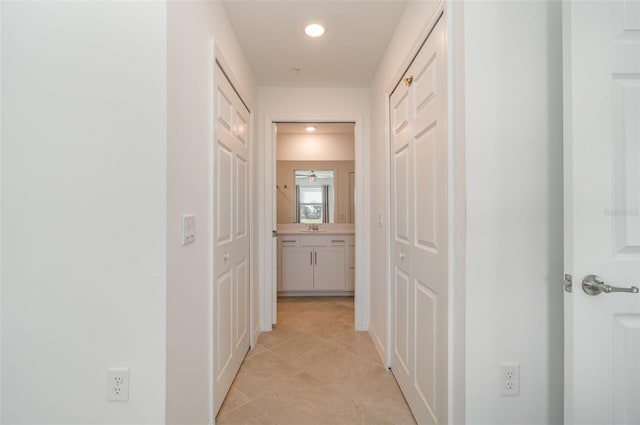 hall featuring sink and light tile patterned floors