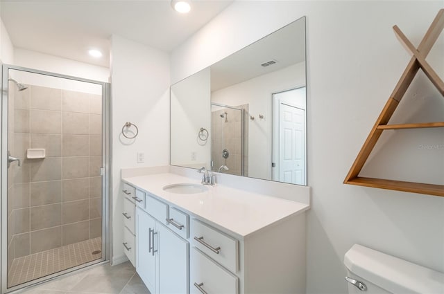 bathroom featuring toilet, vanity, tile patterned floors, and a shower with shower door